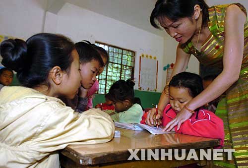 2004年12月3日，云南省西雙版納傣族自治州景洪市勐罕鎮(zhèn)曼聽村的黨員、教師玉罕約（右一）在給村小學的孩子們補習功課。曼聽村是一個典型的傣族村寨，近兩年來，曼聽村黨支部大力加強基層黨組織建設，村黨支部充分發(fā)揮黨員在經(jīng)濟建設中的作用，帶領群眾學科技、調(diào)結構、闖市場，開辦科技講座和黨課培訓，使得村里經(jīng)濟發(fā)展迅速，人民生活明顯改善。 新華社發(fā) 